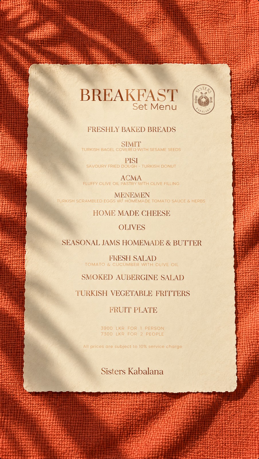 The breakfast set menu — Prata type in terracotta on cream, the Sisters Kabalana crest, laid on rust-coloured linen.